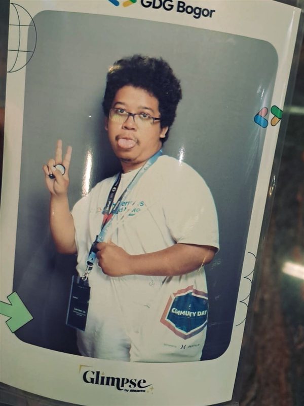 Reva at an IT community event, lanyard on, posing with a peace sign